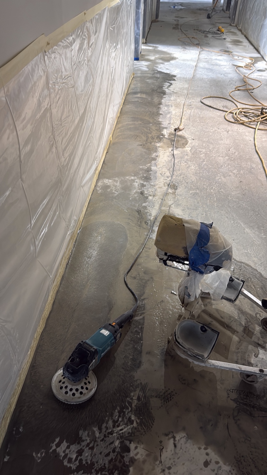 Edge grinder beside a protected wall during concrete floor polishing in Des Moines