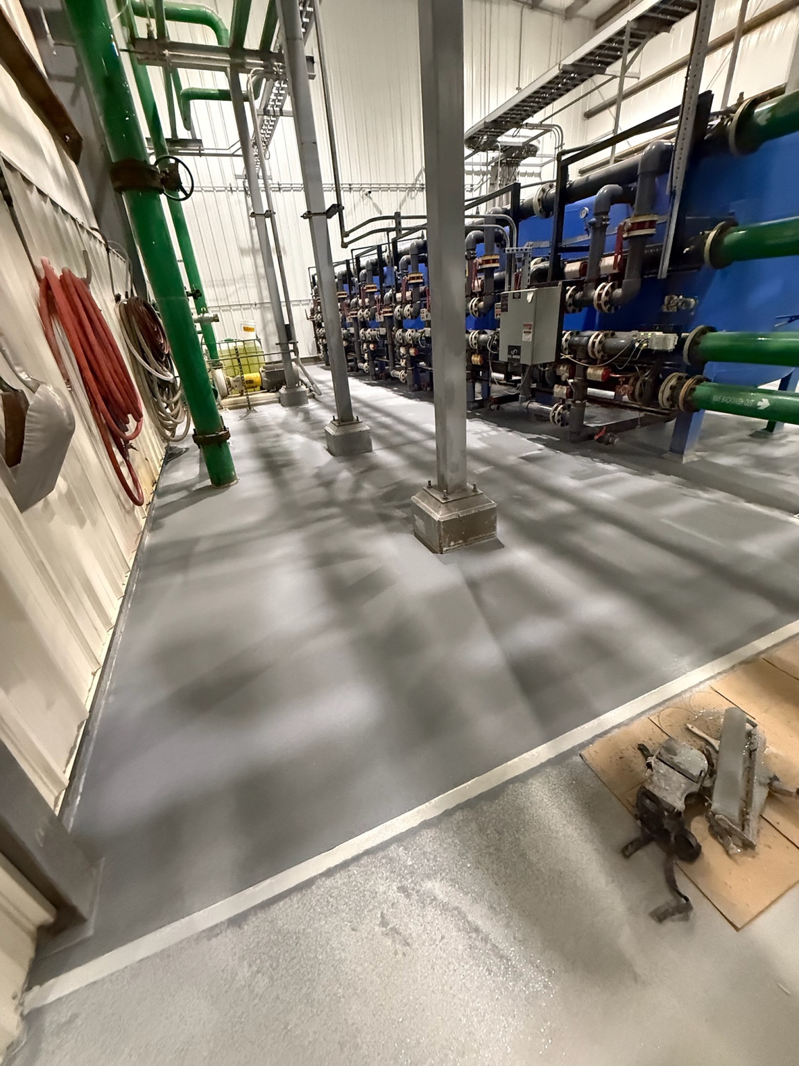 Gray epoxy floor coating around pipes and equipment in an Iowa industrial mechanical room