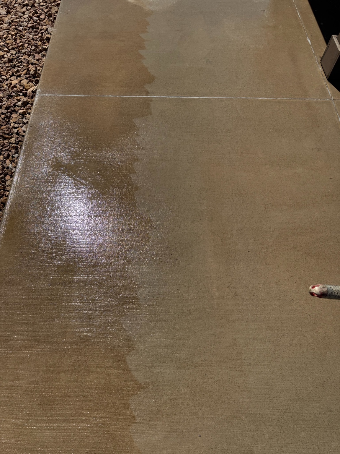 Fresh concrete sealer being applied beside an unsealed section in Des Moines