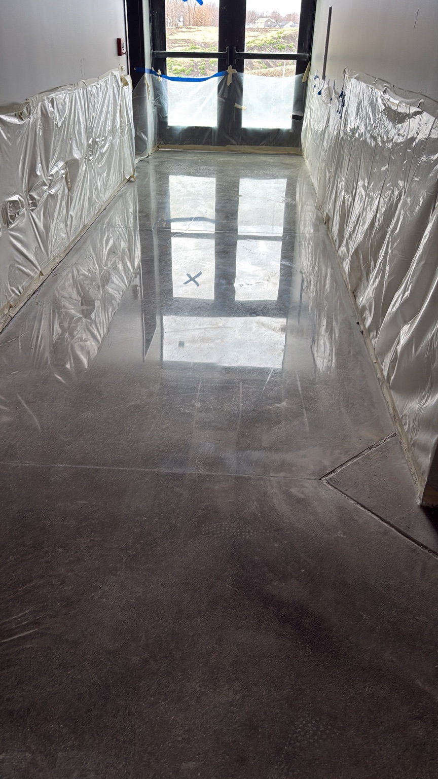 High-gloss polished concrete hallway reflecting the entrance doors in Des Moines