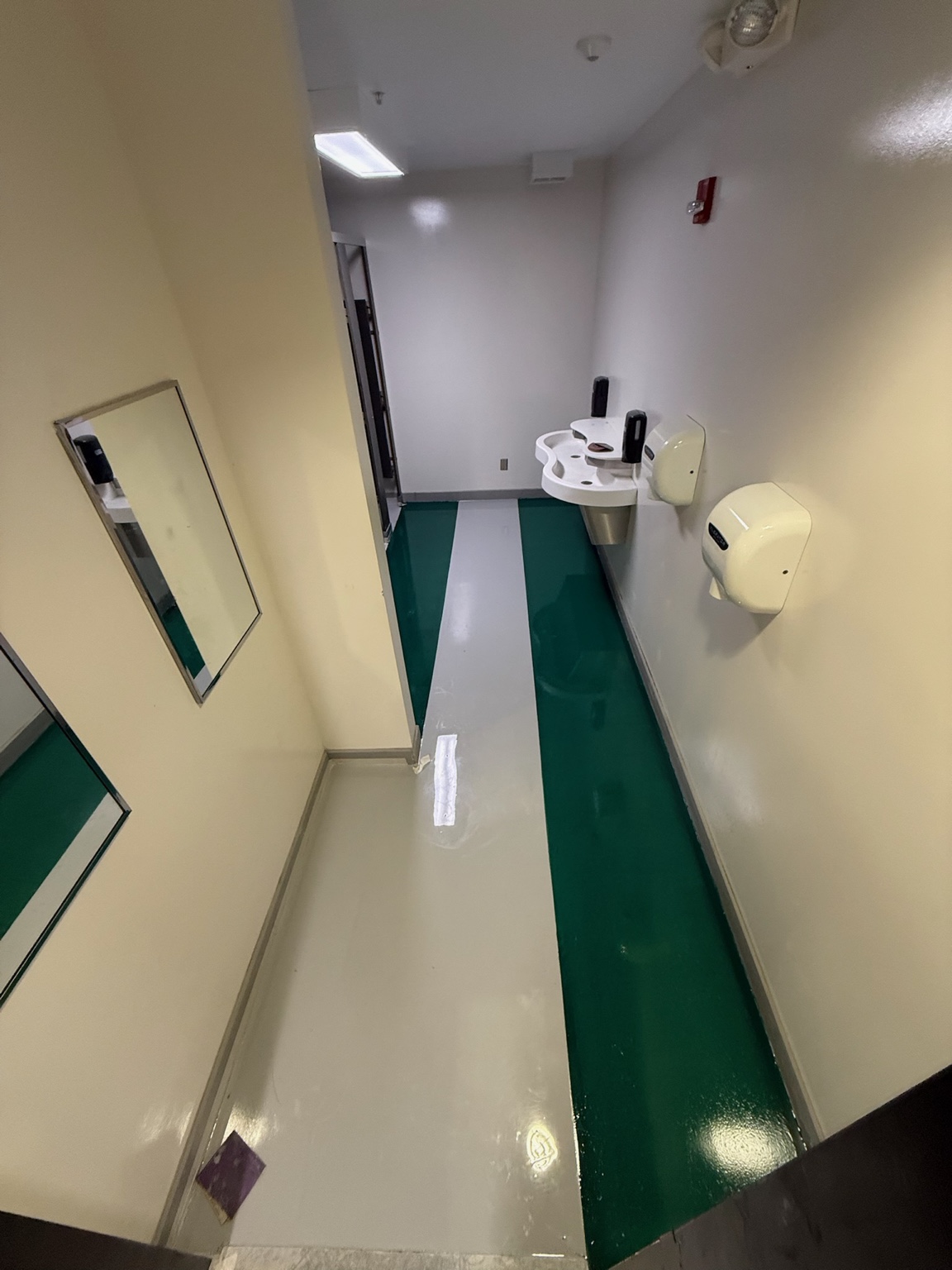 Glossy green and white decorative epoxy flooring in an Iowa commercial restroom