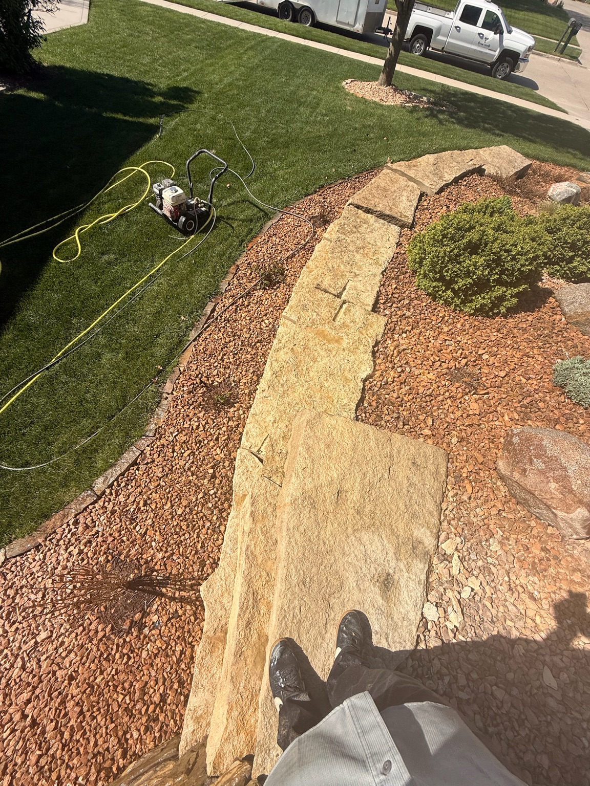 Pressure washing equipment beside a cleaned stone retaining wall in Des Moines