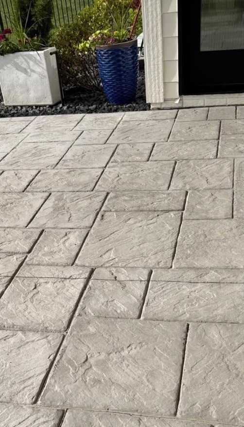 Faded stamped concrete patio with worn sealer before resealing in Des Moines